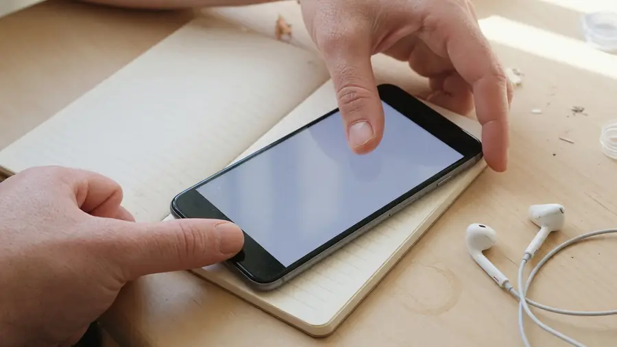 Reader holding phone beside a notepad for match notes